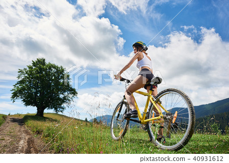 Young happy woman riding bicycle in the mountains at summer day 40931612