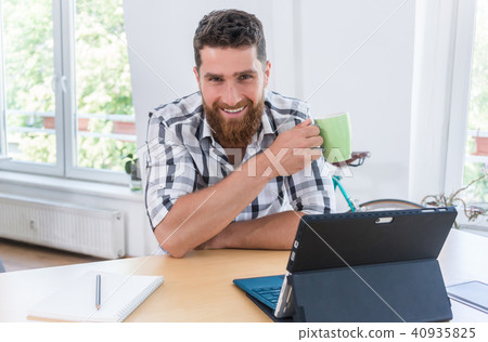 Portrait of a confident self-employed young man sitting at desk  40935825