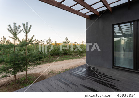 Side view of an open veranda in front of a modern forest cottage. Pine young forest under the sunset 40935834