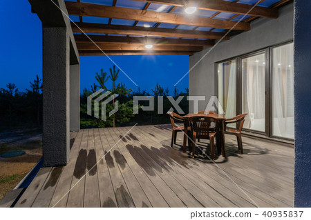 Side view of an open veranda in front of a modern forest cottage. Pine young forest under the sunset 40935837