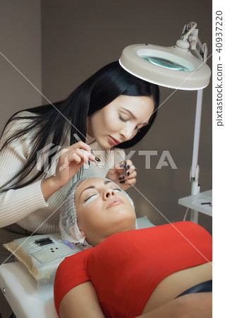 young woman working on eyelash extensions young woman working on eyelash extensions 40937220