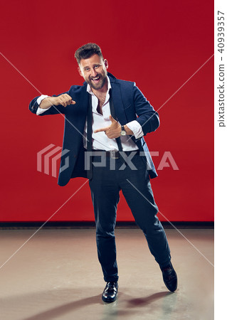 The happy business man pointing to left, half length closeup portrait on red background. The happy business man pointing to left, half length closeup portrait on red background. 40939357