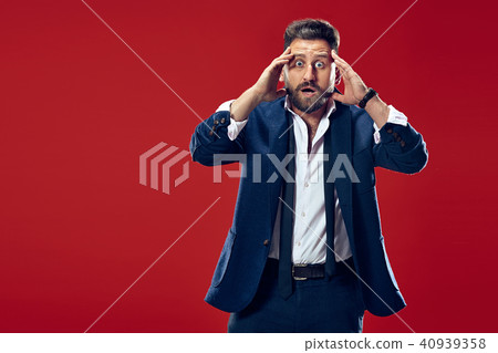 The young attractive man looking suprised isolated on red 40939358