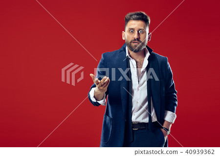 The young attractive man looking suprised isolated on red The young attractive man looking suprised isolated on red 40939362