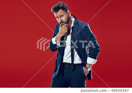Suspiciont. Doubtful pensive man with thoughtful expression making choice against red background 40939367