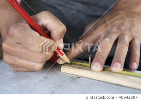young man making a mark in a wood strip 40942697