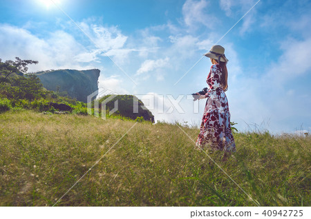 Woman standing on meadow and holding camera Woman standing on meadow and holding camera 40942725