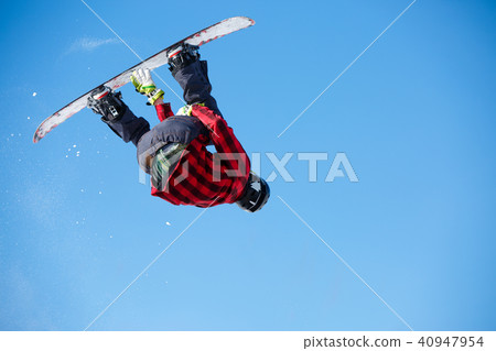 Photo from below of jumping man with snowboard and blue clear sky 40947954