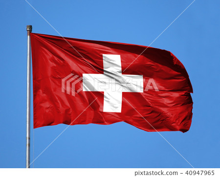 National flag of Switzerland on a flagpole in front of blue sky National flag of Switzerland on a flagpole in front of blue sky 40947965