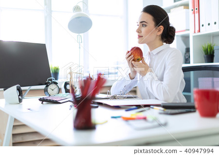 Young girl in the office working with documents and holding an apple. 40947994