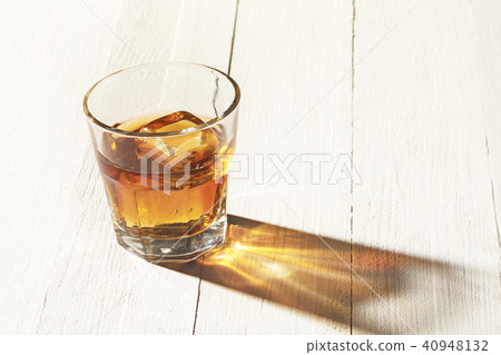 Whiskey in glass, ice cub served in a short glass on white table Whiskey in glass, ice cub served in a short glass on white table 40948132