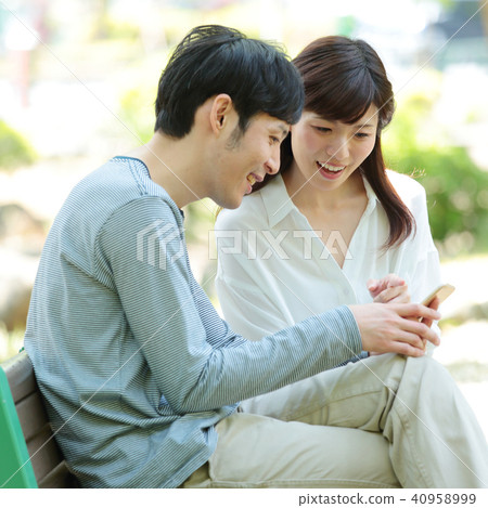 看一個智能手機的夫婦在公園 40958999