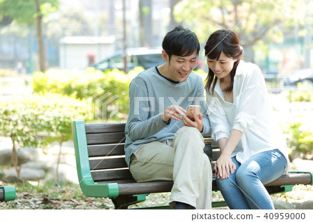 看一個智能手機的夫婦在公園 40959000
