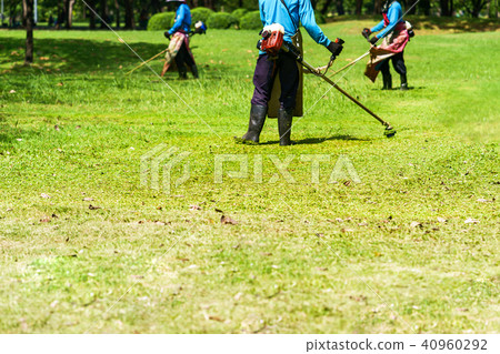 Mower worker cutting grass in green field 40960292