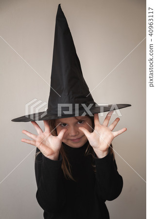 Girl in black witch costume posing over wall 40963117