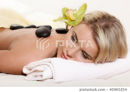 Woman relaxing with flower and hot stones Woman relaxing with flower and hot stones 40965854