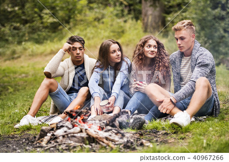 Teenagers camping in nature, sitting at bonfire. 40967266