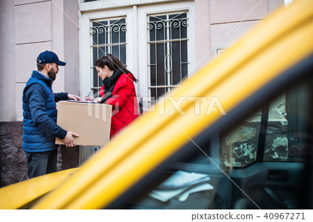 Woman receiving parcel from delivery man at the door. Woman receiving parcel from delivery man at the door. 40967271