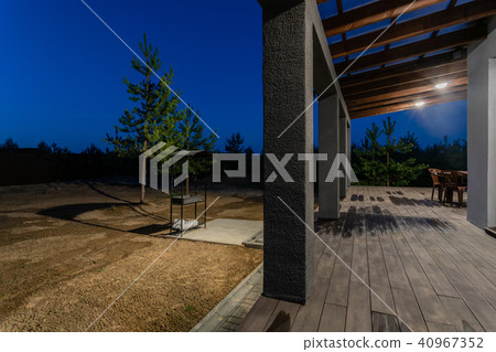 Side view of an open veranda in front of a modern forest cottage. Pine young forest under the sunset 40967352
