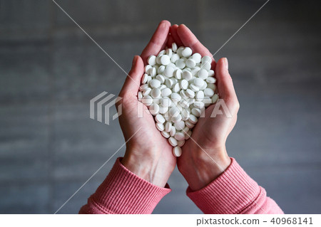 Woman's holding cupped hand full of pills 40968141