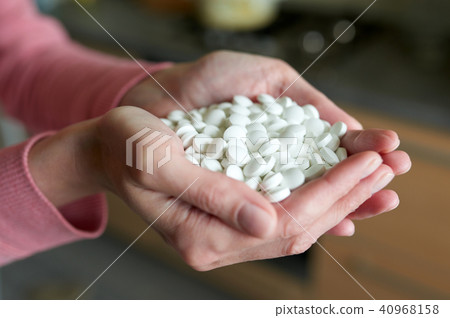 Woman's holding cupped hand full of pills 40968158