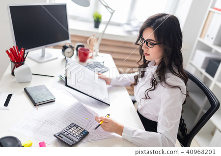 A young girl sits at the office desk and checks documents. A young girl sits at the office desk and checks documents. 40968201