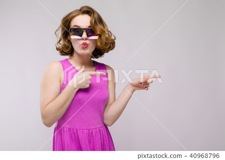 Charming young girl in pink dress on gray background. Cheerful girl in square glasses. The girl 40968796