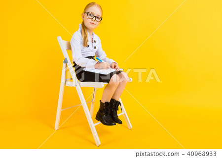 Girl with red hair on a yellow background. A charming girl in transparent glasses sits on a white Girl with red hair on a yellow background. A charming girl in transparent glasses sits on a white 40968933