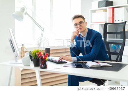Young man sitting at desk in office and working on computer. Young man sitting at desk in office and working on computer. 40968937