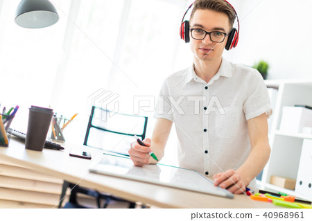A young man with glasses and headphones draws a marker on the magnetic board. A young man with glasses and headphones draws a marker on the magnetic board. 40968961