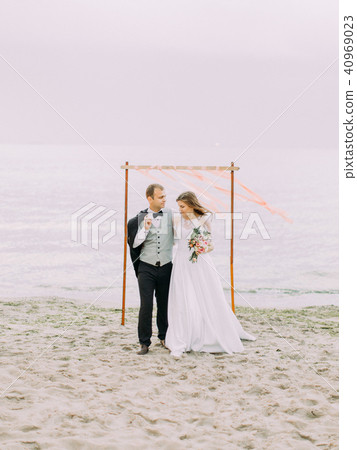 Happy newlyweds walking on the beach during the sunset. 40969023