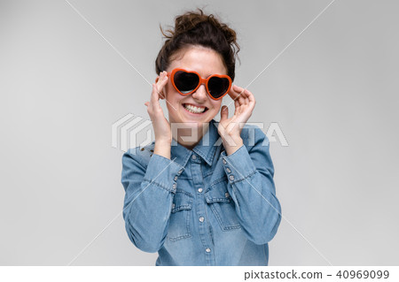 Young brunette girl with glasses in the form of a heart. The hairs are gathered in a bun. The girl 40969099