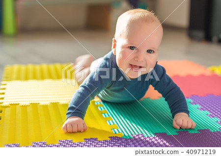 Infant baby boy playing on colorful soft mat. Little child making first crawling steps on floor. Top 40971219