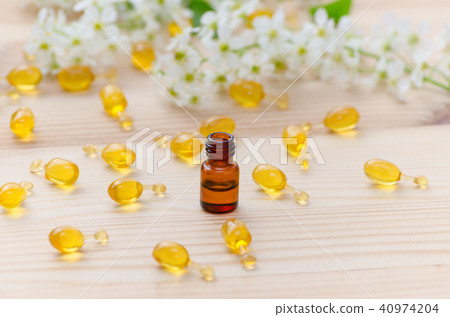 little brown bottle with neroli essential oils, gold capsules of natural cosmetic and flowers 40974204