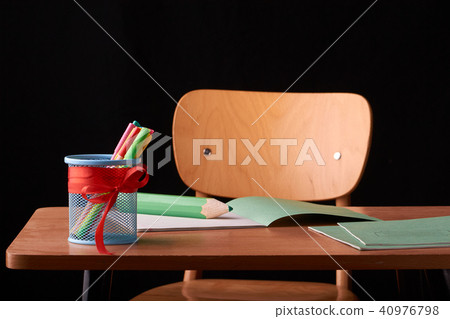 A glass with colored pens on a wooden table 40976798