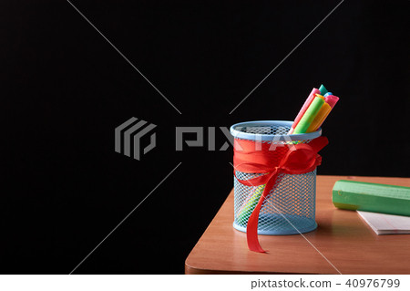 A glass with colored pens on a wooden table A glass with colored pens on a wooden table 40976799