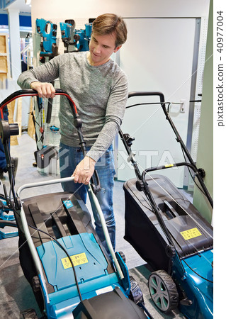 Man chooses lawn mower in store 40977004