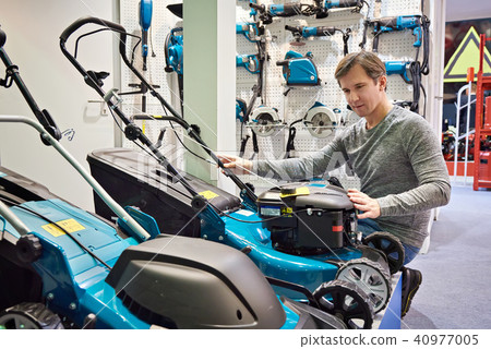 Man chooses lawn mower in store Man chooses lawn mower in store 40977005