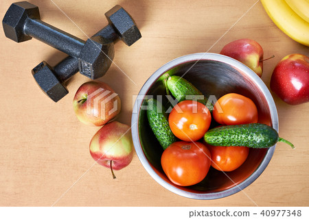 Fruits, vegetables and dumbbells on table Fruits, vegetables and dumbbells on table 40977348