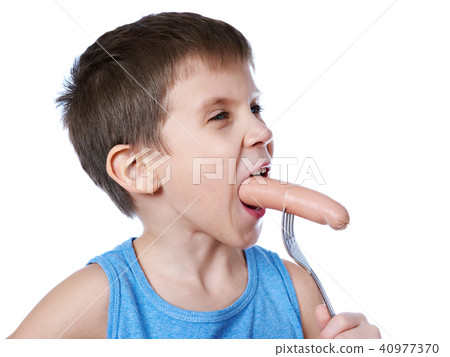Little boy eating a sausage from fork isolated 40977370