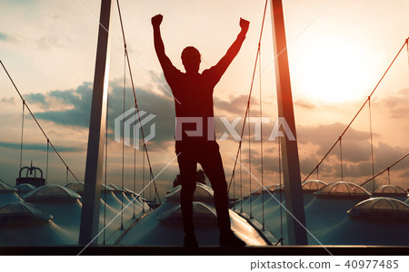 Winner concept: Silhouette champion hand holding gold medal reward against blurred sport stadium 40977485