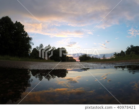The sky at sunset is reflected in a puddle, 40978421