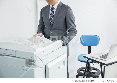 A man in a suit who works in front of a copier 40986849