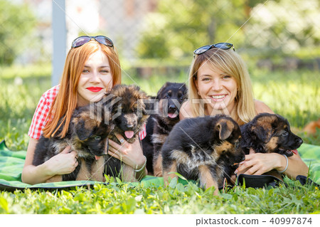 Two young women with puppies of german shepherd Two young women with puppies of german shepherd 40997874