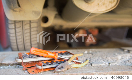 Set of tools in front of mechanic underneath a car screwing details on under tray 40998046