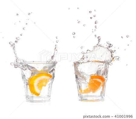 orange splashing into glass of water on white  41001996