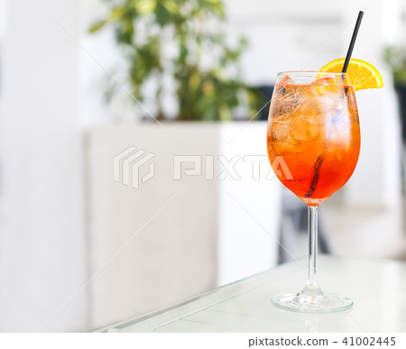 Orange cocktail with straw on white table 41002445