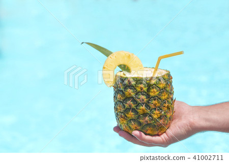 Exotic pineapple cocktail near pool. Pina colada Exotic pineapple cocktail near pool. Pina colada 41002711