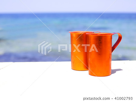 Two orange cups on sea background Two orange cups on sea background 41002793