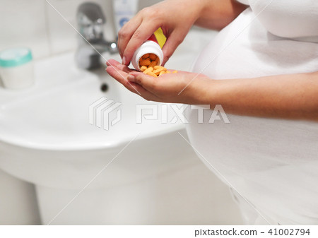 Pregnant woman in bath room taking pills Pregnant woman in bath room taking pills 41002794